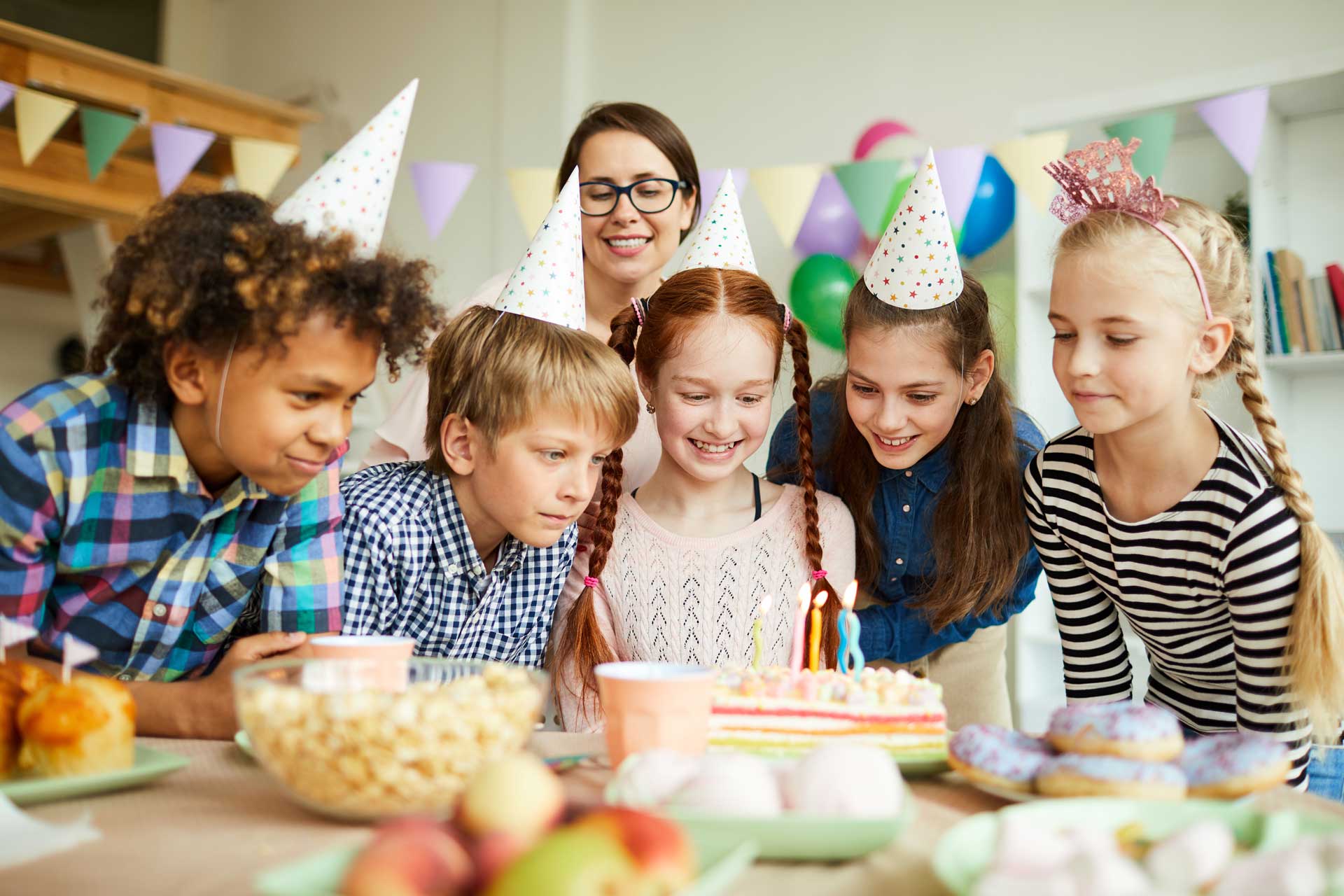 Kids birthday party with hats, cake, and decorations