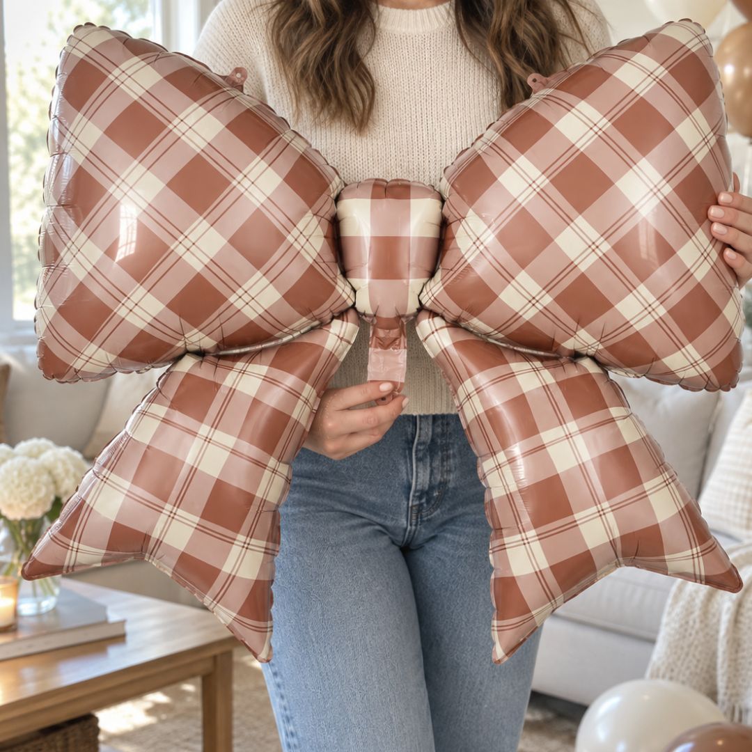 Party Paradise Store brown gingham plaid bow foil balloon held by a person for fall party decorations.