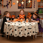 Children in costumes sitting at a round table with a Party Paradise Store Halloween table cover featuring ghost prints