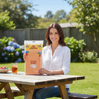 A woman holding a Party Paradise Store orange reusable plastic table cover package at an outdoor picnic table.